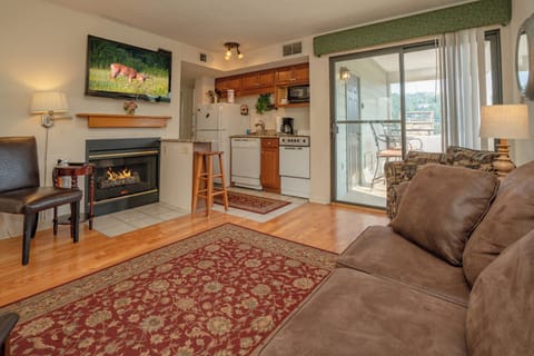 Sink into the plush sofa and enjoy your cozy retreat, complete with a warming fireplace and sunlit balcony access just beyond the glass doors.
