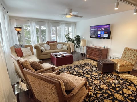 Expansive living room with smart TV and lights, lots of seating & natural light
