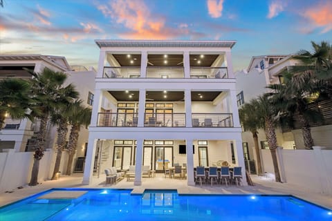 Modern three-story beachside villa with illuminated pool and tropical palms creates an elegant coastal retreat.