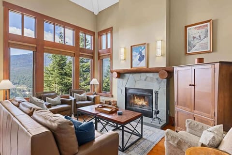 - Inviting living room with floor-to-ceiling windows framing breathtaking mountain views  
- Cozy stone fireplace and leather seating create a perfect après-ski retreat  
- Sunlit space ideal for relaxing with friends or enjoying peaceful evenings