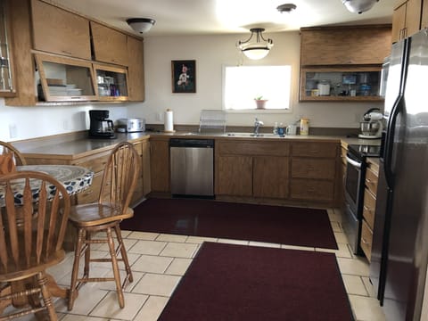 Warm tile floor in modern well equipped kitchen with pub table