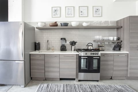Kitchen with oven, refrigerator, and shelving with glass plates and bowls.