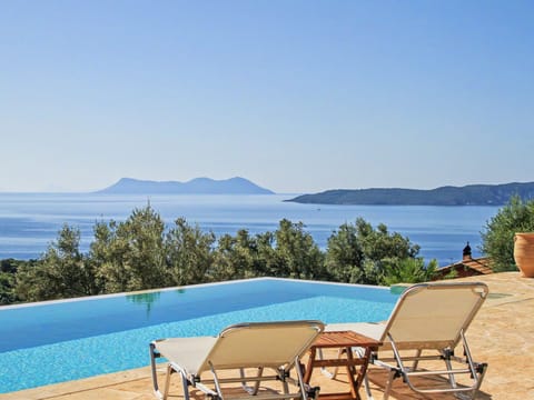 Lounge beside the infinity pool with panoramic sea and mountain views.