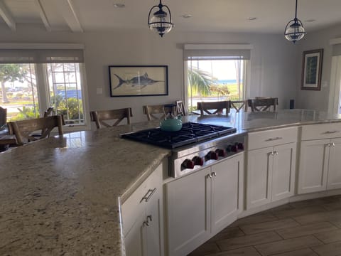 Alternate view of kitchen, with ocean view, range, and bar seating.