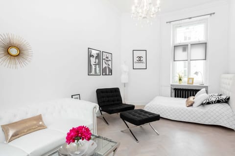 Bright and comfortable living area with an armchair, stylish sofa, and elegant bed for two people.