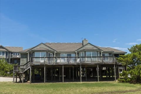 This elevated beachfront home features spacious decks and coastal architecture, offering a welcoming retreat surrounded by natural greenery and ocean breezes in a tranquil setting.