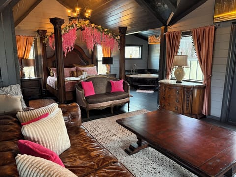Unwind in your romantic suite featuring a stunning four-poster bed with floral canopy, cozy seating area, and luxurious soaking tub.