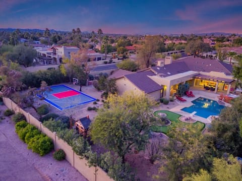 Stunning aerial view of a luxury desert estate featuring a sparkling pool, sport court, and resort-style amenities nestled in the Scottsdale landscape.