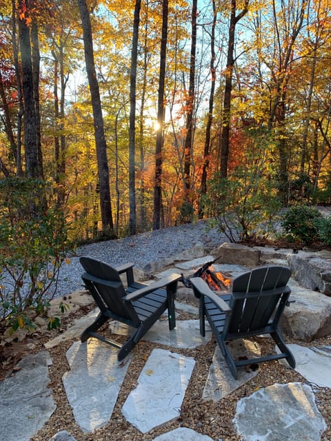 Landscaped firepit boasts natural stone & boulders + ambient landscape lighting