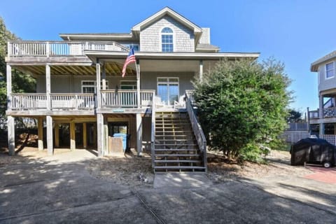 Coastal vacation home with classic shingled exterior, wrap-around porches on multiple levels, and generous parking area—your beach retreat awaits just steps from the shore.
