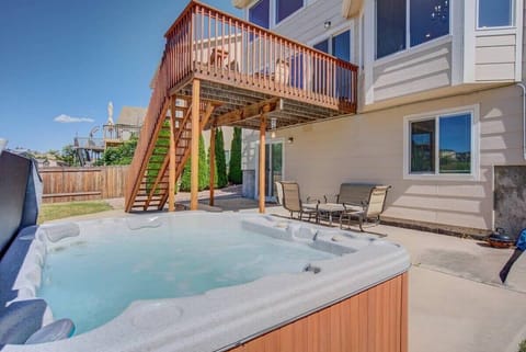 Outdoor hot tub bubbling beside the house, with stairs leading up to a raised wooden deck above. An inviting spot to sink into warm water, stretch out, and unwind in the open air after a full day.