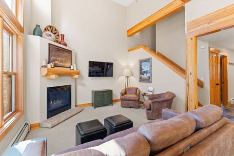 Relax in your cozy living room featuring exposed wood beams, a warming fireplace, and plush seating perfect for unwinding after mountain adventures.