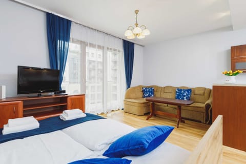 A bedroom featuring a wooden bed with blue bedding, bedside tables, and curtains in a matching blue tone.