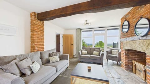 The cozy living area features original exposed oak beams, comfortable sofas, and a large Smart TV for relaxing evenings.