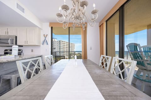 Dining area featuring a rustic table, stylish chairs, and a view of the beach through large sliding glass doors