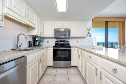 Kitchen features granite countertops, stainless appliances, and a view of the beach through large windows