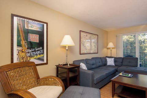 Unwind in your cozy living room featuring a plush sectional sofa, vintage ski poster, and warm natural light streaming through the windows.
