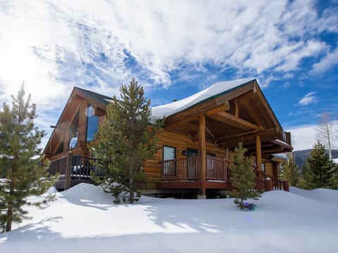 Mountain lodge nestled in pristine snow with evergreens and dramatic winter sky backdrop.