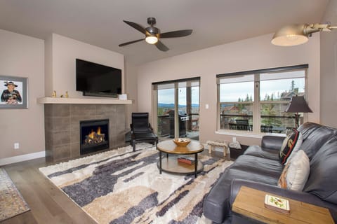 Unwind in your spacious living room with crackling fireplace, plush leather seating, and stunning mountain views through floor-to-ceiling windows.