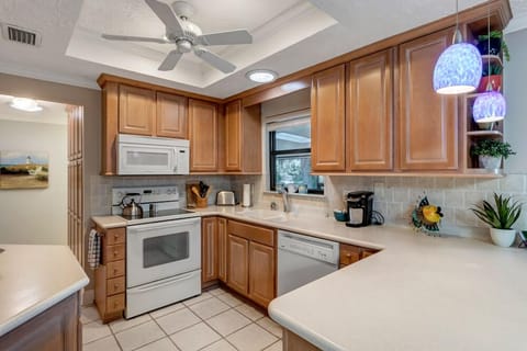 - Whip up vacation meals in this cheerful kitchen with warm wood cabinetry and bright tile
- Fully equipped with stove, microwave, toaster, and coffee station for every need
- Blue pendant lights add a fun pop above the wide breakfast bar