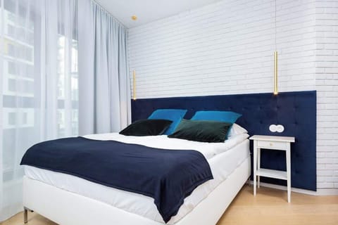 A modern bedroom with navy and white bedding on a double bed, complemented by light wooden furniture and a bright atmosphere.