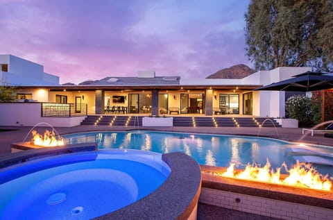 Entertainment paradise awaits in the expansive backyard patio. With three fire features, a heated pool with a Baja lounge, a hot tub, BBQ, bocce ball court, putt-putt green, ping pong table, and water features and mountain views.