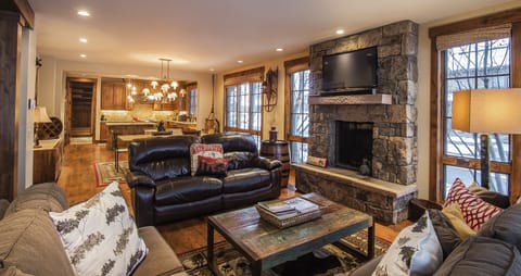 Sink into plush leather sofas by your crackling stone fireplace, where warm wood tones and mountain views create the perfect retreat for cozy evenings after your adventures.