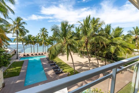 Balcony View: Breathtaking pool and ocean backdrop surrounded by lush palm trees!
