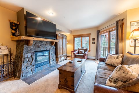 Cozy up by your stone fireplace while watching the big screen TV in this warm living room with mountain views.