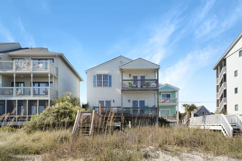 Charming beachfront homes with private walkways to the sand, featuring colorful coastal architecture and oceanfront balconies.