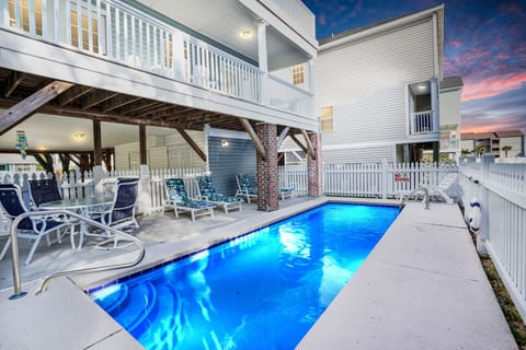 Dive into your private pool surrounded by a charming deck with lounge chairs, perfect for relaxing under colorful skies.