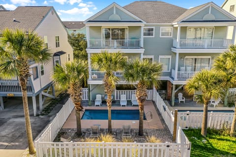 Elevated coastal properties with private swimming pool and tropical palm landscaping in a residential beach neighborhood.