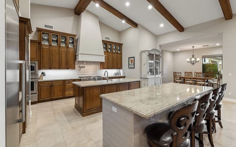 Kitchen with dual granite islands, bar seating, stainless fridge, and prep space