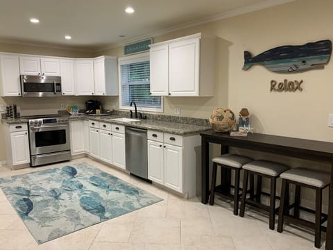 Spacious kitchen with everything you need, including spices. Enjoy a stainless steel island, new Emeril cookware, coastal-inspired dinnerware. Not in the mood for cooking? There are plenty of restaurants within walking distance!