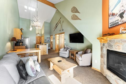 Relax in your cozy mountain retreat with vaulted ceilings, rustic stone fireplace, and ski-themed décor creating the perfect alpine getaway atmosphere.