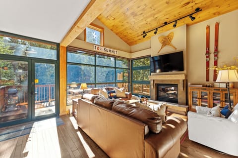 Cozy up by the crackling fireplace in this alpine living room with panoramic windows framing mountain views.