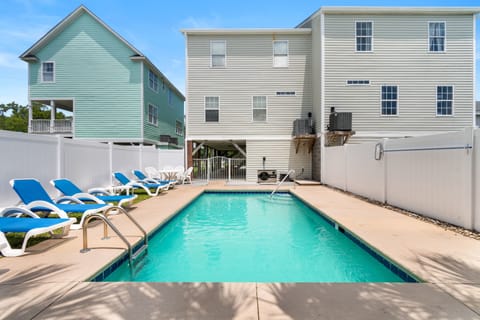 Dive into crystal-clear waters in your private backyard oasis, where blue loungers await your poolside relaxation moments.