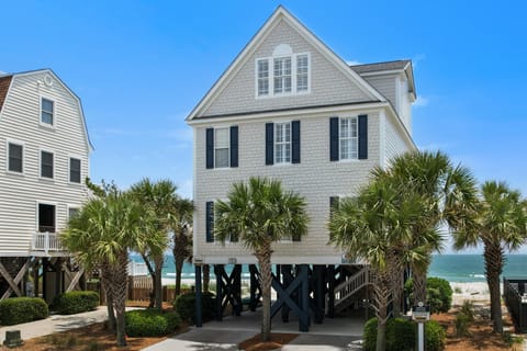 Coastal charm meets elevated living in this stunning beachfront home with palm trees framing ocean views.