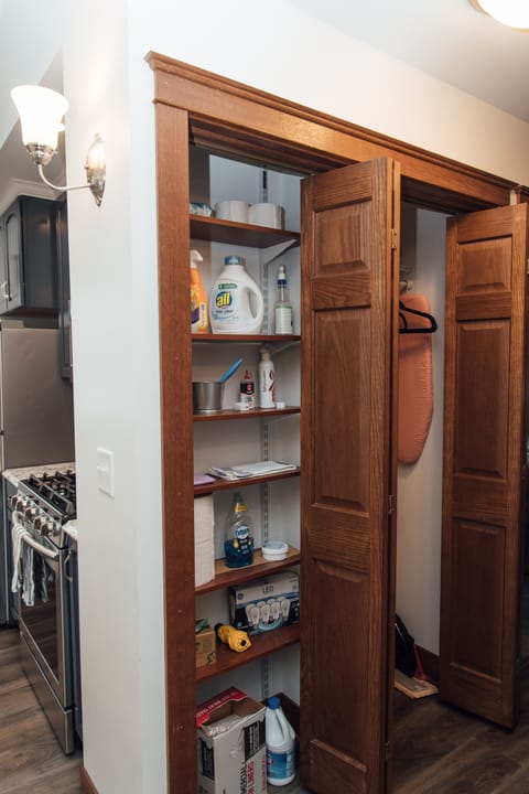 Hall closet for hanging coats (background) and pantry with household supplies.