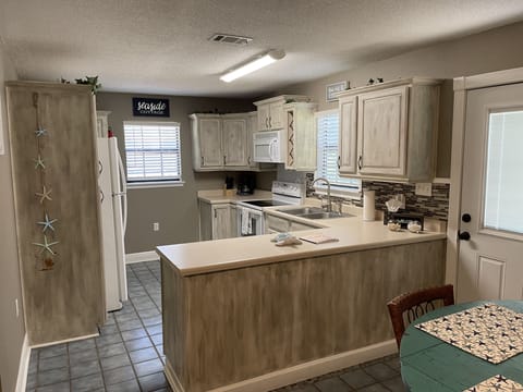 full kitchen with lots of custom chalk painted cabinets and large counter top