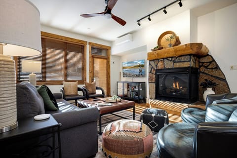 Cozy up by the crackling stone fireplace in this warm living space, perfect for après-ski relaxation with plush seating and mountain charm.