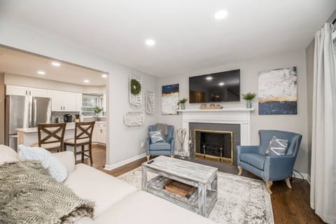 Charming family room featuring a 65" TV, cozy fireplace, and bright white finishes. Includes a comfortable sleeper sofa, creating a warm and versatile space for relaxation or movie nights.