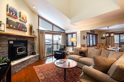 Cozy up in your spacious living room featuring a stone fireplace, plush sectional sofa, and warm ambiance perfect for relaxing evenings together.