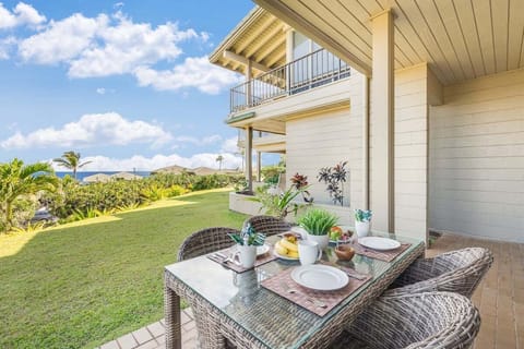 Outdoor dining on a covered patio with ocean views and tropical garden setting.