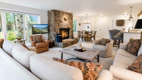 Settle into plush seating by the stone fireplace, where mountain views and warm lighting create your perfect retreat for cozy evenings and shared stories.