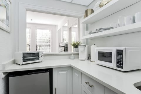 Fully stocked kitchenette. Microwave, Oven Toaster, mini fridge, Keurig coffee maker, glasses, plates, and cutlery.
