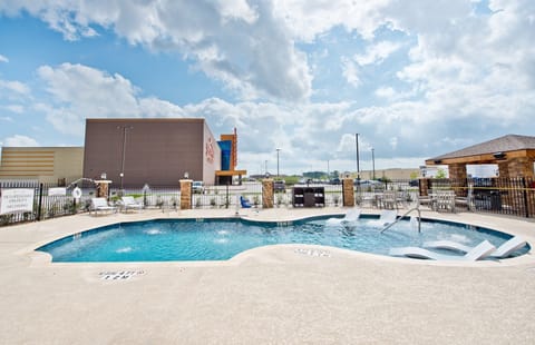Heated outdoor pool with lounge chairs and patio seating — a cool escape after exploring Humble