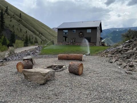 View of the outdoor fire pit and rustic sitting area (logs, rocks) 