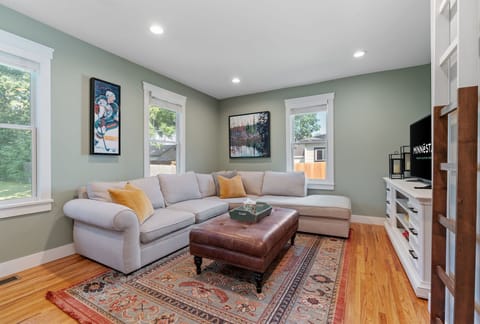 Sink into this plush sectional where sage walls and warm wood floors create your perfect retreat for movie nights.