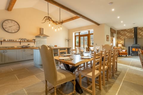 Red Stag Lodge, Little Massingham: Kitchen/ dining/ sitting area with hand-made dining table, antler chandelier, large leather sofas and wood burning stove